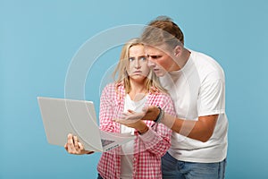 Young perplexed couple friends guy girl in white pink empty blank t-shirts posing isolated on pastel blue background