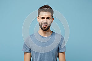 Young perplexed disgusted irritated man in casual clothes posing isolated on blue wall background, studio portrait