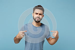 Young perplexed unconfident man in casual clothes posing isolated on blue background, studio portrait. People sincere