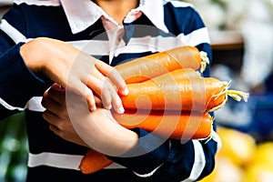 Young Person Carrying Armful of Fresh Organic Carrots Farmers Market Closeup Vegetables Food