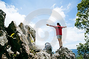 Young person hiking female standing on top rock, Backpack woman looking at beautiful mountain valley at sunlight in summer,