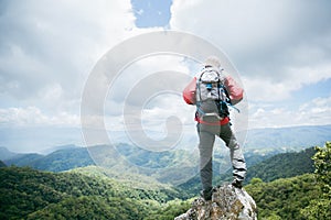 Young person hiking male on top rock, Backpack man looking at beautiful mountain valley at sunlight in summer, Landscape with