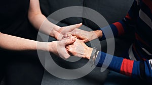 Young person holding hands of an elderly woman