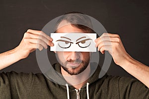 Young person holding paper with angry eye drawing