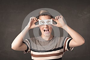 Young person holding paper with angry eye drawing