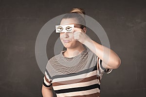 Young person holding paper with angry eye drawing