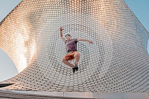 Young person jumping in front of the modern and architectural Soumaya building