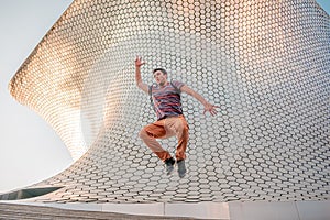 Young person jumping in front of the modern and architectural Soumaya building photo