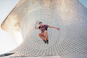 Young person jumping in front of the modern and architectural Soumaya building photo