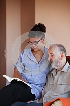 Young person reading to elderly man