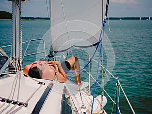 Young person sunbathing on a sailboat under the sail