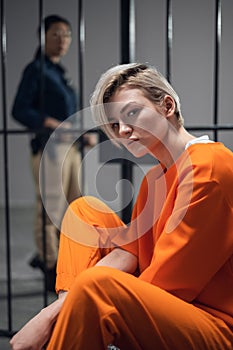 A young pert blonde with piercings is in jail for a cyber crime. Head portrait on the background of a prison cell.