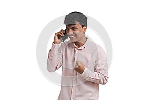 Young peruvian man celebrating a victory while speaking on the phone, isolated.