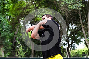 Young peruvian man warming up by stretching arms before exercise.