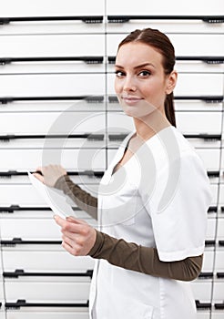 Young pharmacist with prescription. Portrait of young female pharmacist smiling with prescription at pharmacy.