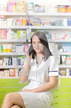 Young pharmacist woman using a app on a smart phone Pharmaceutical background. Drugstore. Pills and medicine.