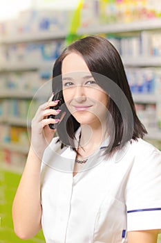 Young pharmacist woman using a app on a smart phone Pharmaceutical background. Drugstore. Pills and medicine.