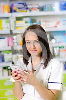 Young pharmacist woman using a app on a smart phone Pharmaceutical background. Drugstore. Pills and medicine.