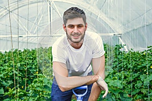 Young photogenic guy is working in a greenhouse.