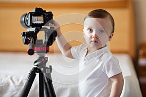 Young photographer child taking photos with camera on a tripod