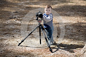 Young photographer child taking photos with camera on a tripod