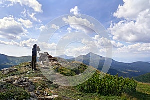 Young photographer man standing on top of cliff taking pictures of the ridge mountain range of Chernogor in Ukraine. Carpathian