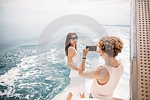 Young photographer taking picture of his girlfriend on seaboat