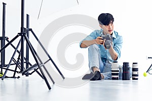 Young photographer is taking pictures in the studio with a digital camera