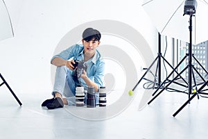 Young photographer is taking pictures in the studio with a digital camera