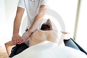 Young physiotherapist doing arms treatment to the patient in a physiotherapy room