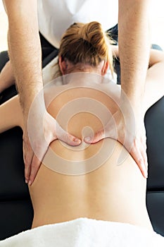 Young physiotherapist doing a back treatment to the patient in a physiotherapy room