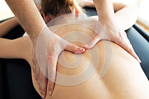 Young physiotherapist doing a back treatment to the patient in a physiotherapy room