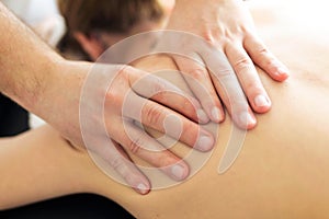 Young physiotherapist doing a back treatment to the patient in a physiotherapy room