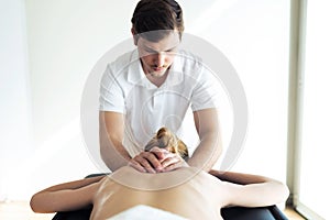 Young physiotherapist doing a back treatment to the patient in a physiotherapy room