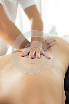 Young physiotherapist doing a back treatment to the patient in a physiotherapy room