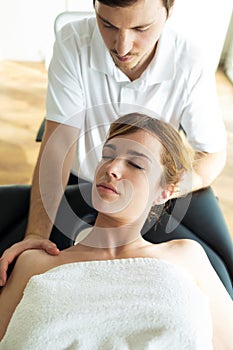 Young physiotherapist doing a neck treatment to the patient in a physiotherapy room