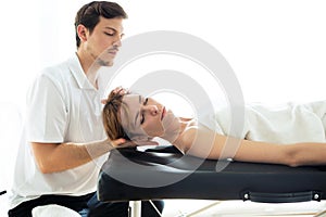 Young physiotherapist doing a neck treatment to the patient in a physiotherapy room