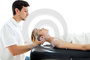 Young physiotherapist doing a neck treatment to the patient in a physiotherapy room