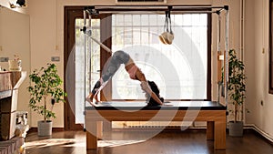 Young Pilates Instructor Woman Exercising on Pilates Reformer. Using a pilates ring