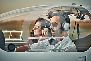 Young pilot and beautiful stewardess sitting together inside airplane cabin waiting for take off