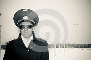 Young pilot with glasses and black coat, bw