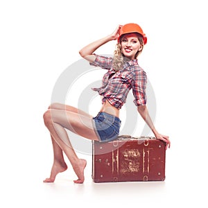 Young pinup woman with suitcase on white