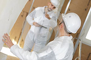 Young plasterer in protective clothing polishing wall