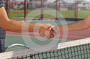 Young players shaking hands on tennis court, only hands can be seen.