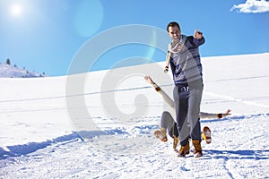 Young playful couple having fun sledging down snow covered hill