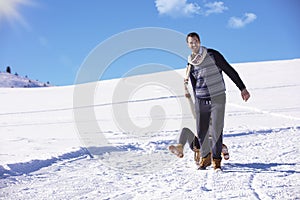 Young playful couple having fun sledging down snow covered hill