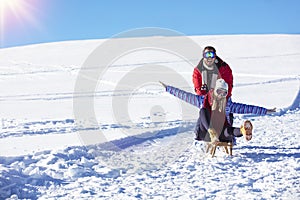 Young playful couple having fun sledging down snow covered hill