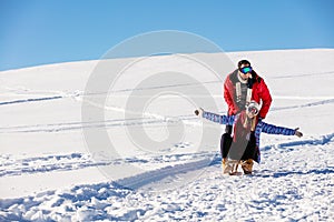 Young playful couple having fun sledging down snow covered hill