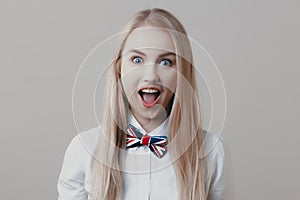 Young playful cute blonde with bow tie opens her mouth in surprise