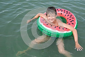 A young playful happy teenage boy relaxing on an inflatable ring ,floaty in the sea during summer vacation